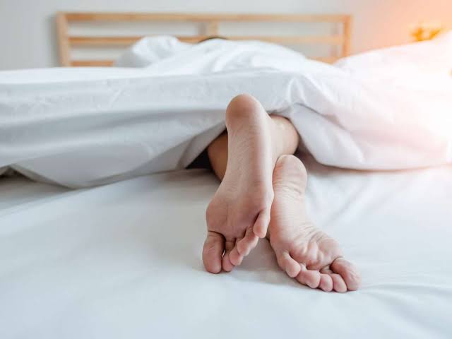 The legs of a person sleeping on a bed
