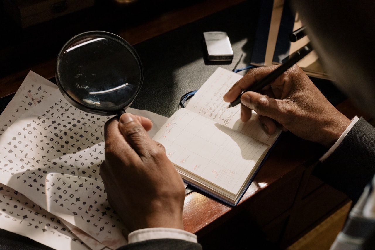 Kryptolog håller i förstoringsglas och antecknar i anteckningsbok