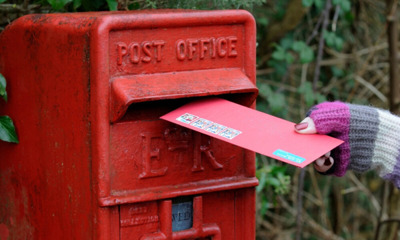Ręka wkładająca list do skrzynki pocztowej