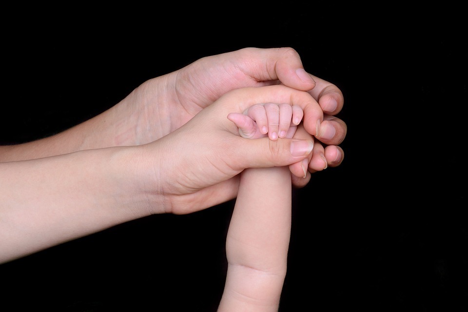 Manos de los padres sujetando una manito del bebé