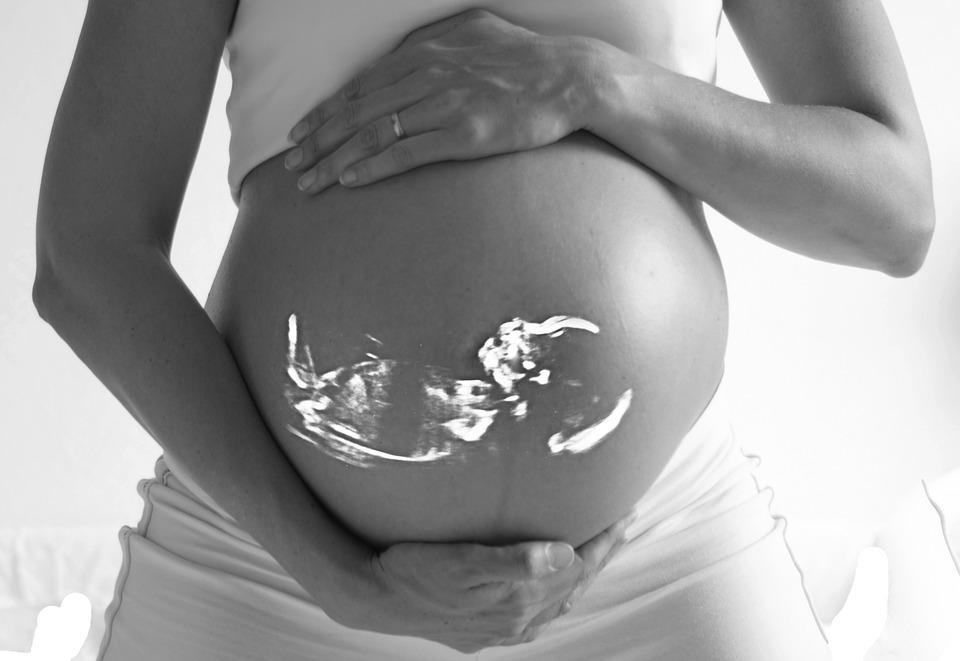 Mujer embarazada con la barriga descubierta y el bebé se muestra como en el ecograma