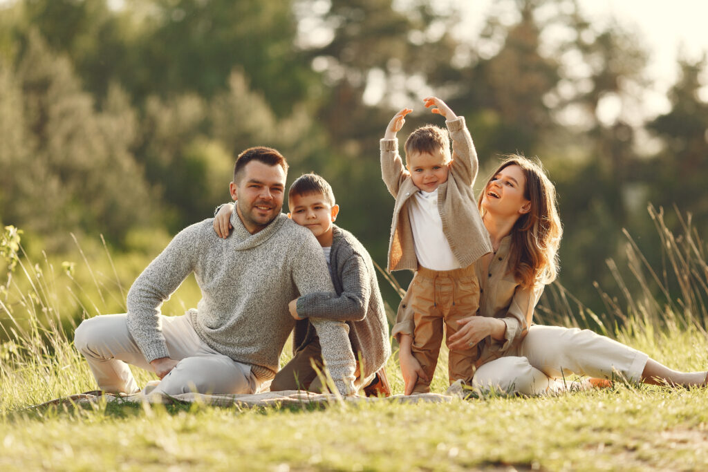 Family with cute little child. Father in a gray sweater. Sunset background.